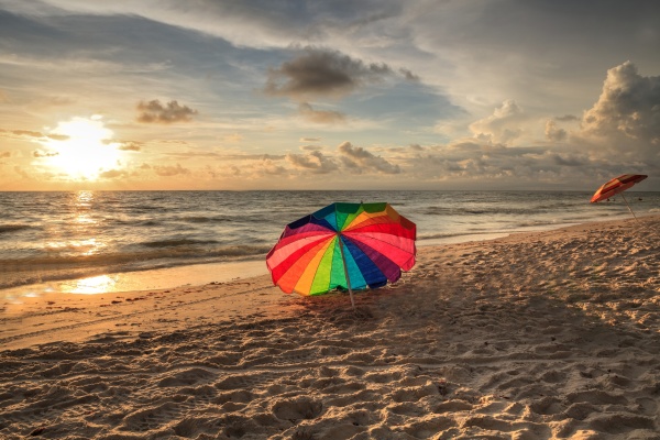 rainbow umbrella on white sand at