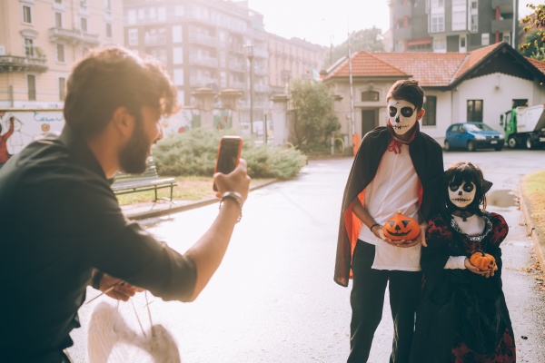 father photographing children in halloween costumes
