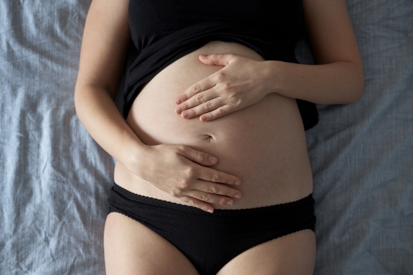 pregnant woman touching stomach while lying