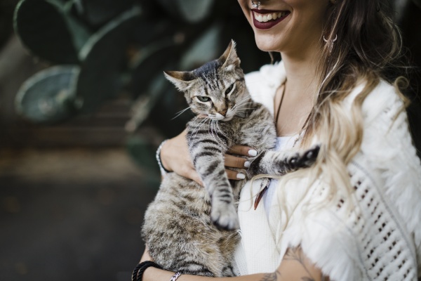 smiling woman holding cat while standing