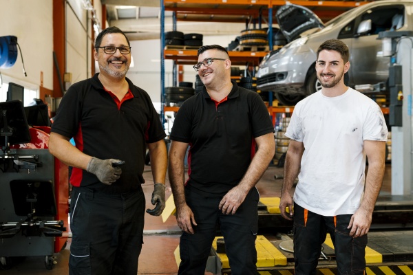 smiling male coworkers standing in auto