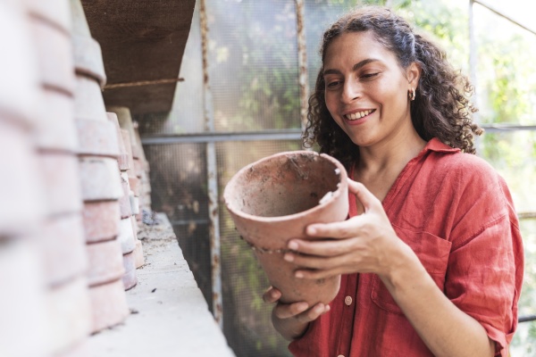 smiling woman holding pot while standing