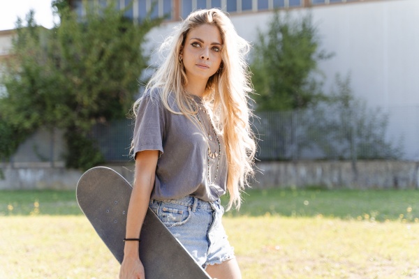 beautiful young blond woman holding skateboard