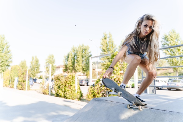 confident young blond woman skateboarding on
