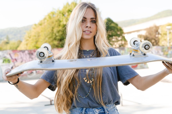 beautiful blond woman holding skateboard while