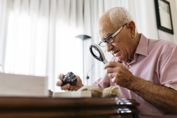 retired senior male using magnifying glass