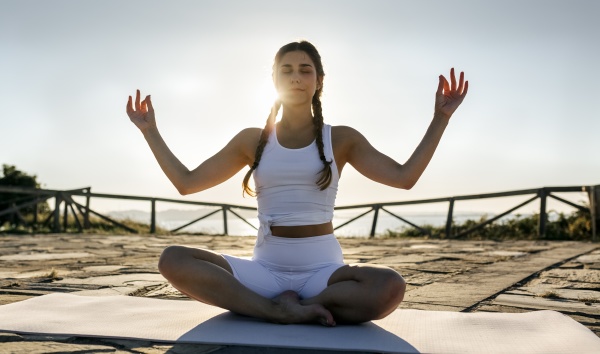 young woman with arms raised meditating