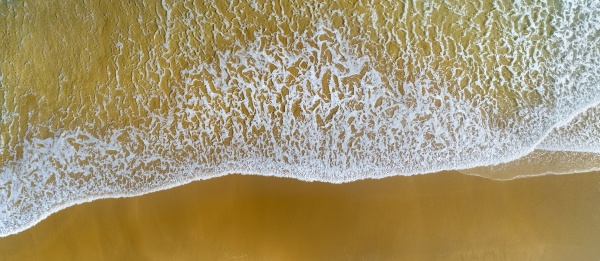 aerial view of wave brushing sand