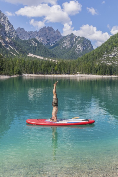 man doing headstand on paddleboard at