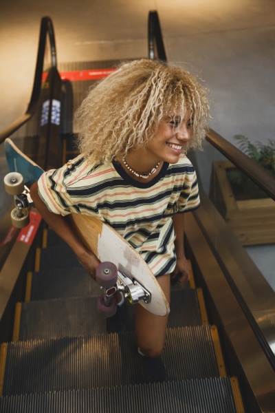 smiling blond hispanic woman holding skateboard