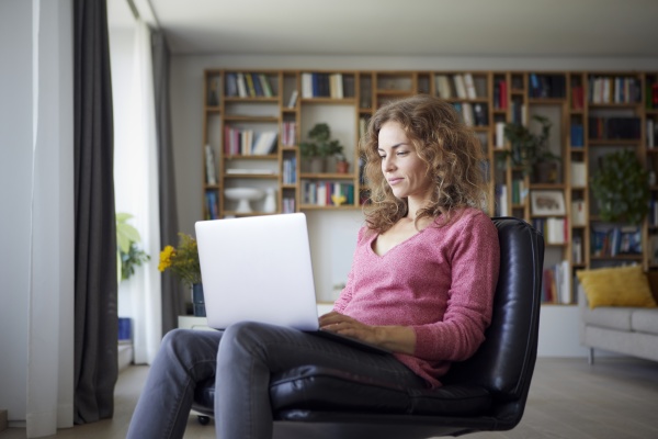 woman using laptop while sitting on