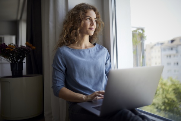 mid adult woman using laptop while