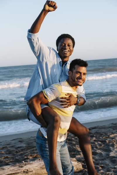 young man carrying friend piggyback on