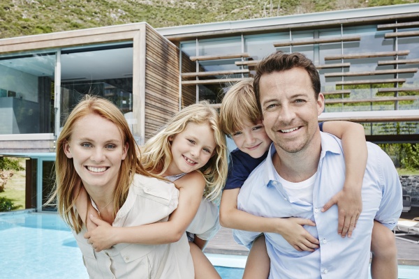 smiling family standing against modern house