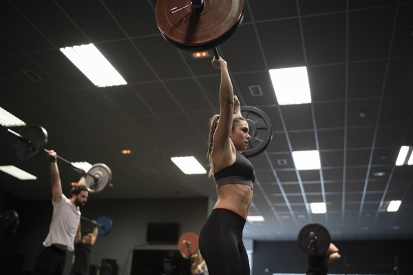 women and men exercising with barbell
