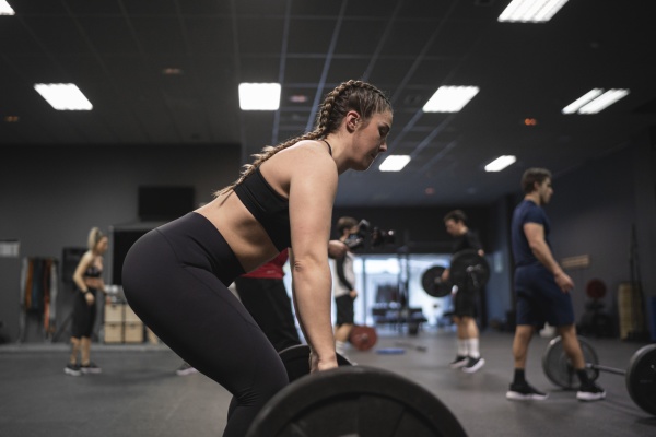 woman picking barbell with people exercising