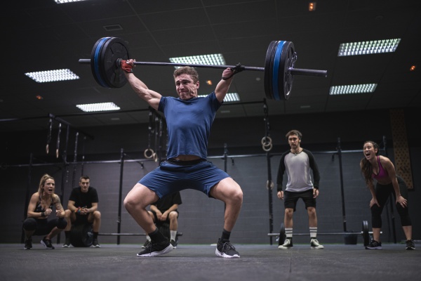 athletes cheering man picking barbell while