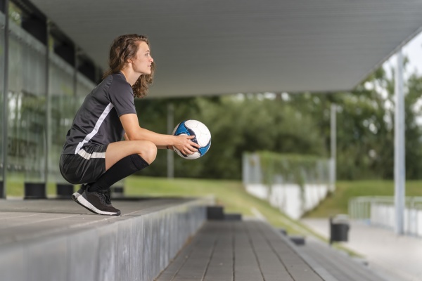 thoughtful female player holding soccer ball