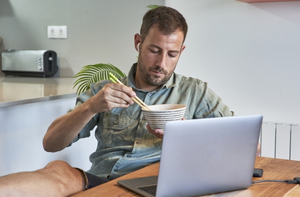 relaxed freelancer eating noodles while sitting