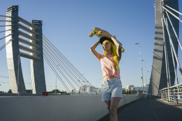 young woman lifting skateboard on head