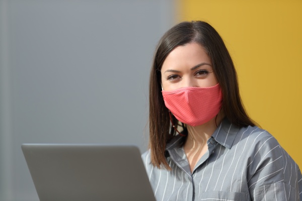 woman with mask and laptop looks