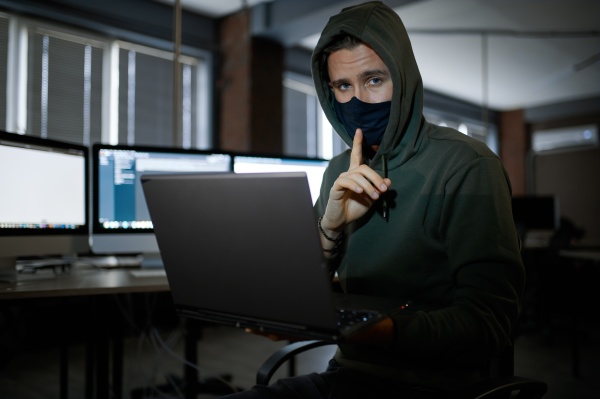 male hacker in hood works on