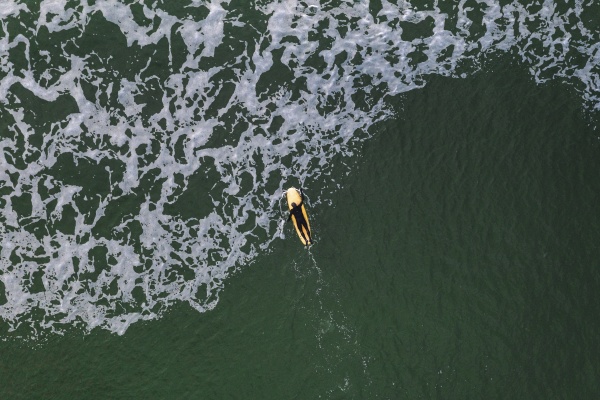 aerial view of surfer paddling out