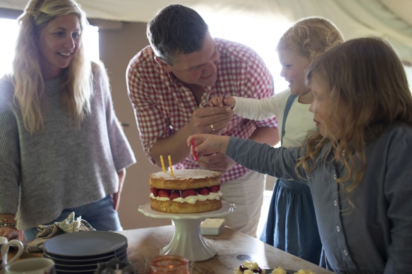 family celebrating birthday with strawberry cake