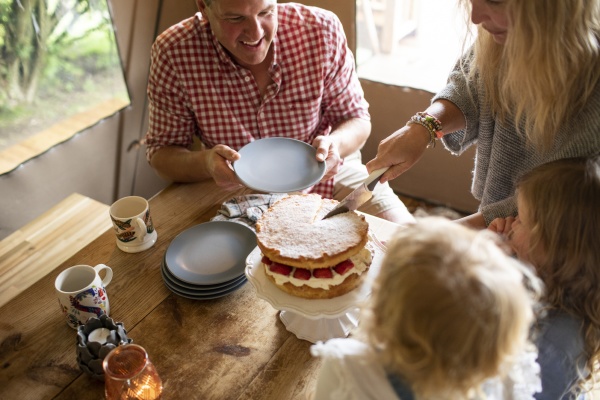 mother serving strawberry cake to family