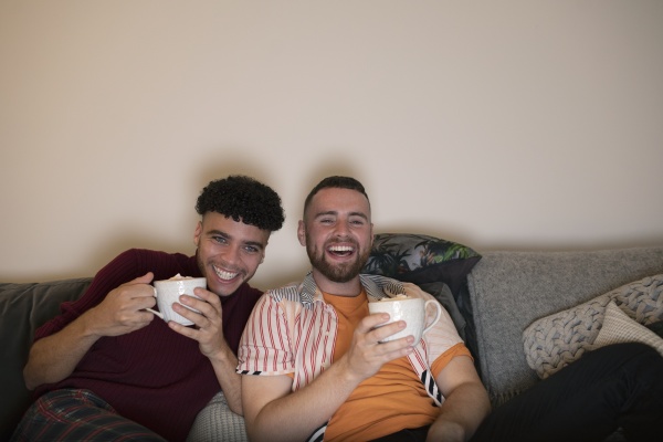 happy gay male couple drinking hot