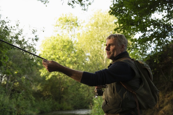 man fly fishing with pole at