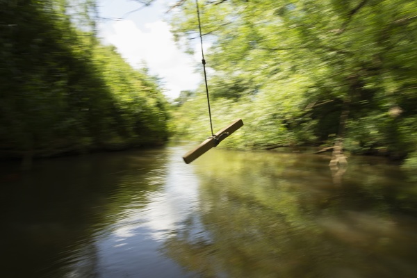 rope swing swinging above green river