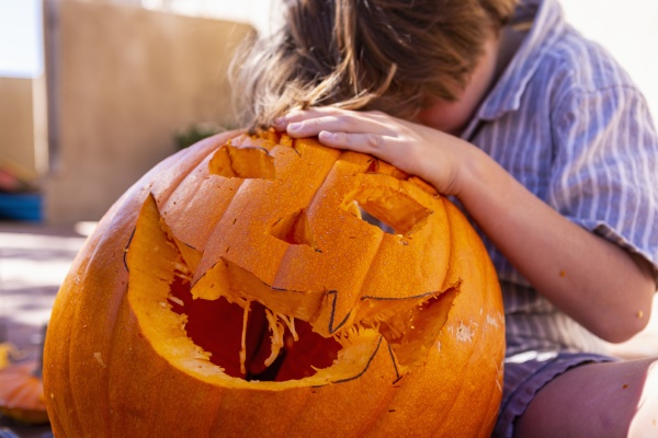 young boy carving pumpkin on patio