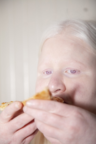 albino woman eating pizza backward