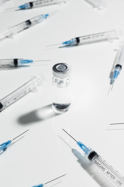 syringes surrounding covid 19 vaccine vial