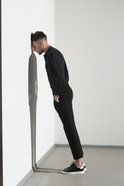 man leaning against white wall