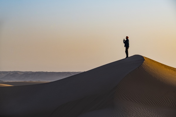 man hiking through the sand dunes