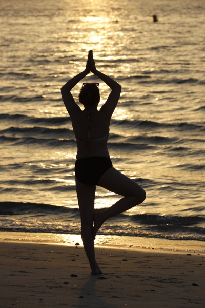 woman practising yoga meditation on beach