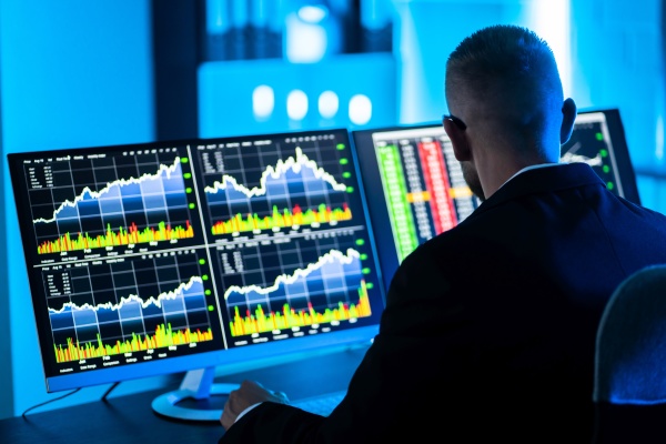 stock trader man using multiple computers