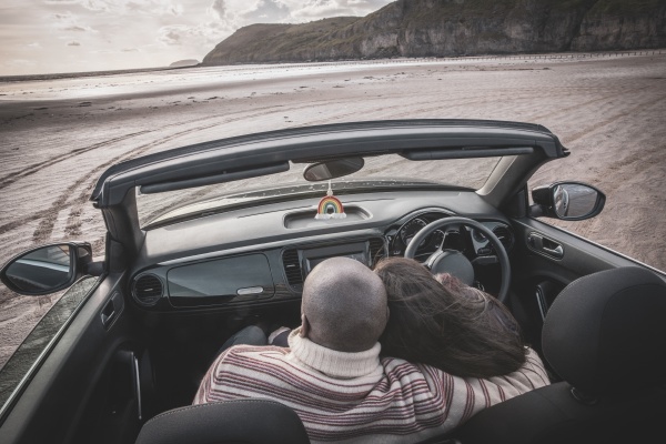 affectionate couple hugging in convertible on