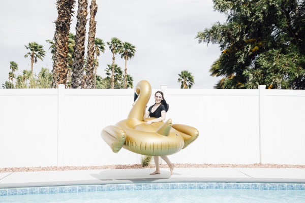 woman holding inflatable swan at poolside