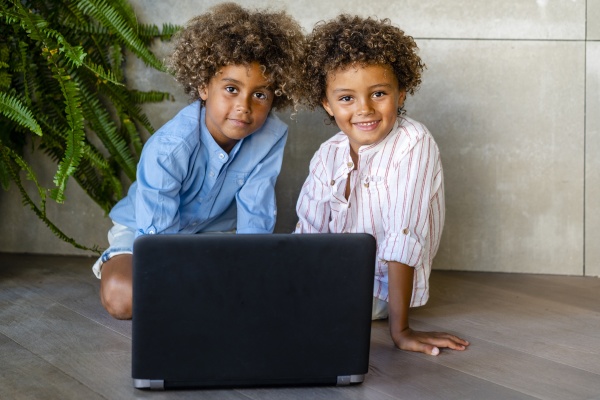 afro brothers with laptop sitting on
