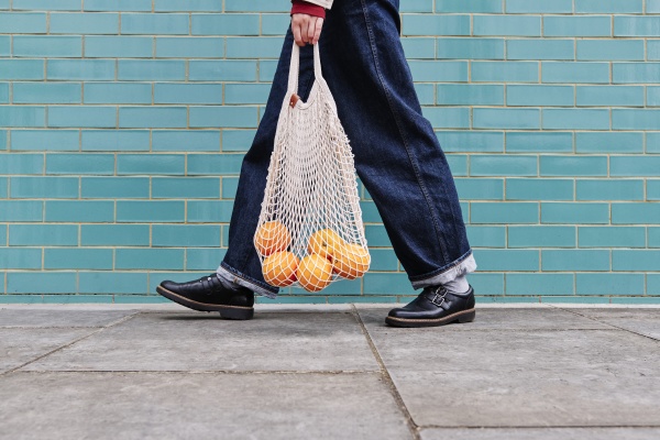 woman walking with oranges in mesh