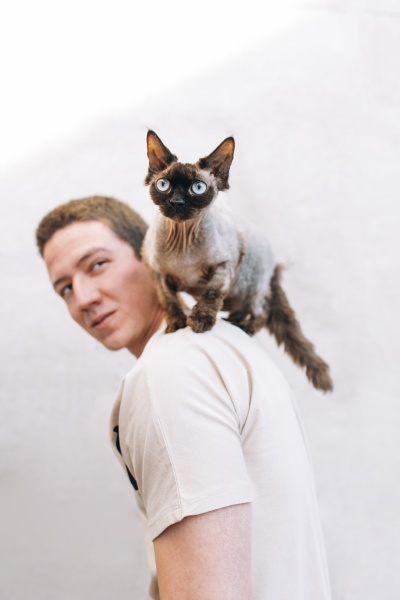 man looking at cat on shoulder