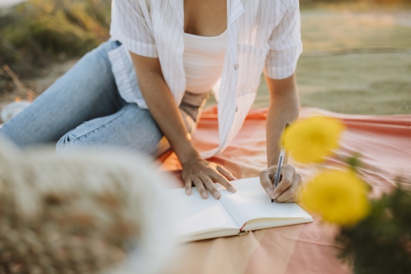 woman writing in book while sitting