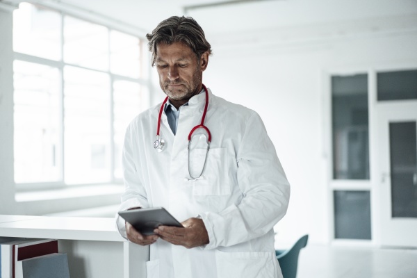 mature male doctor using digital tablet