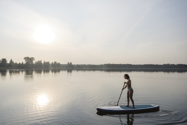 woman doing standup paddleboarding in lake
