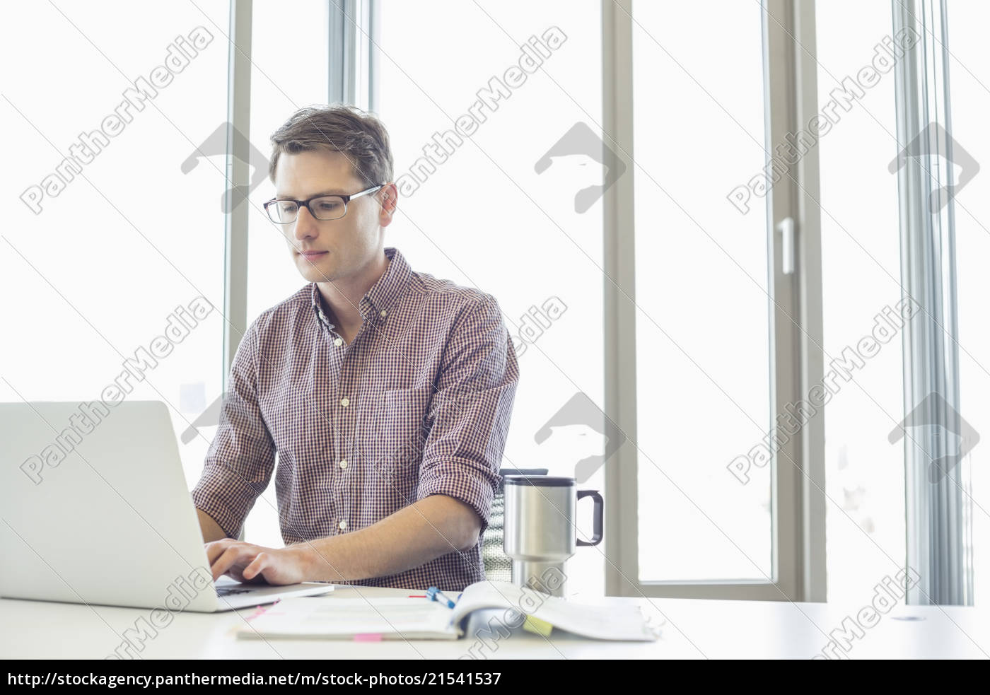 Businessman Working On Laptop At Desk In Creative Stock Photo